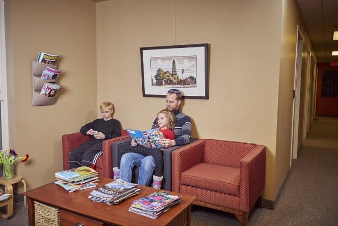Man and 2 children sit in a waiting room 