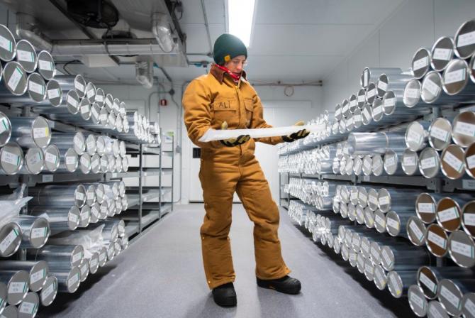 Researcher in a storage room with shelving storing rows of labeled tubes