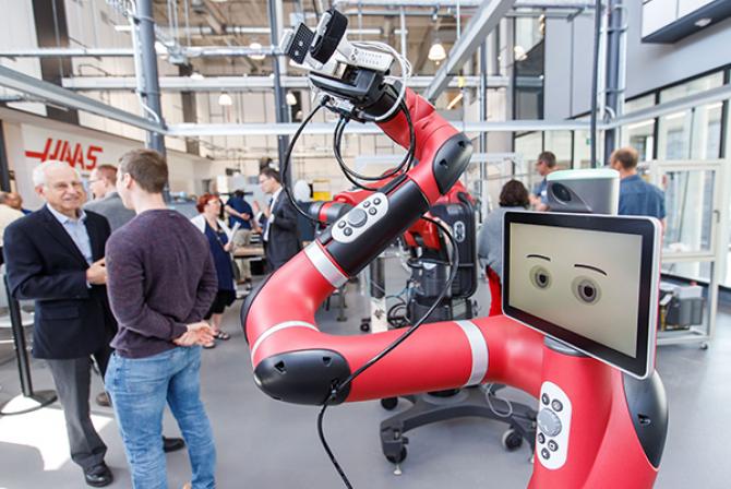 Robot rouge avec bras articulé et écran affichant un visage