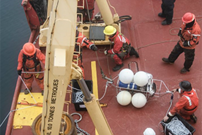 Group of people working with various pieces of equipment on the deck of a boat