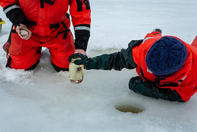 Des chercheurs sur le terrain prélèvent de l'eau d'un trou foré dans la glace