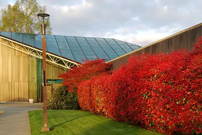 The entrance to a research facility with red bushes against the exterior wall