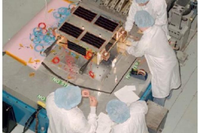Les techniciens de laboratoire préparent un satellite pour des essais
