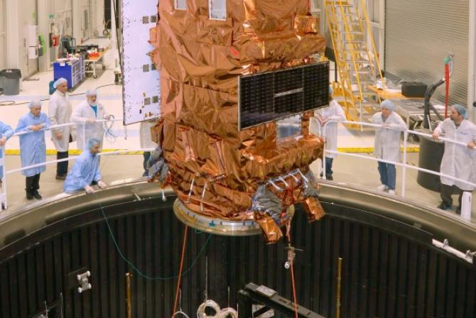 A satellite is lowered into a thermal vacuum chamber 