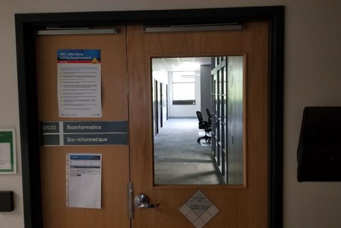 Porte fermée avec fenêtre montrant l’entrée de l’Installation de bio-informatique