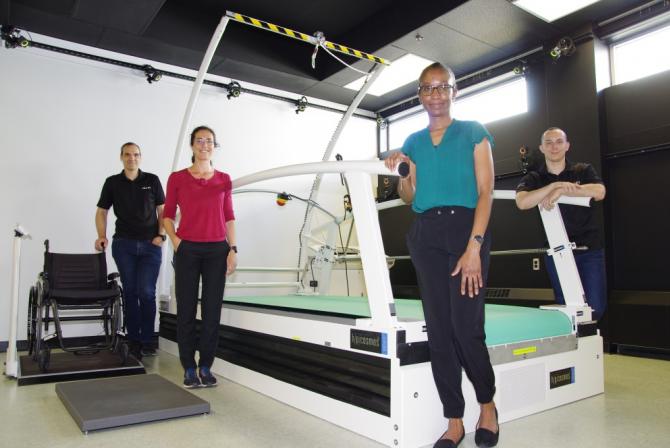 Four people surround a large treadmill