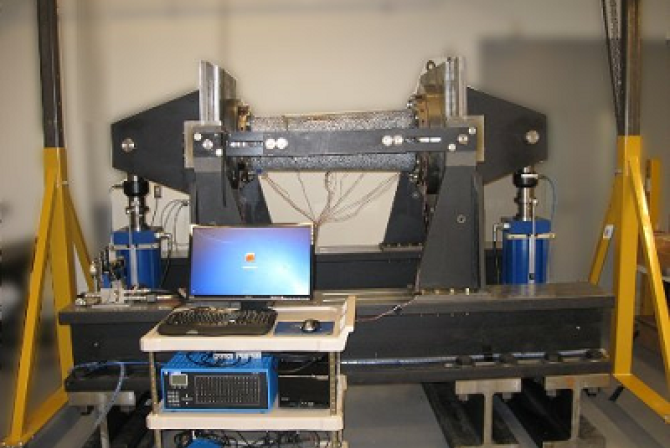 Vue frontale d’une machine à cintrer les tubes, avec un ordinateur et des commandes installés sur un chariot à côté de la machine.
