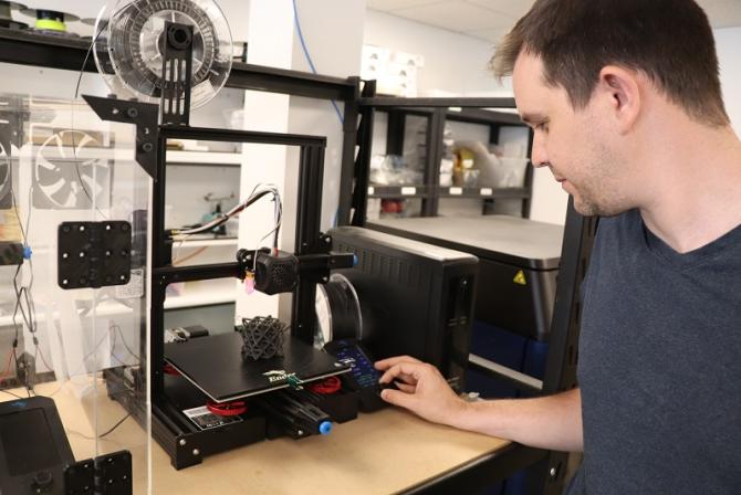 A person operates a 3D printer.