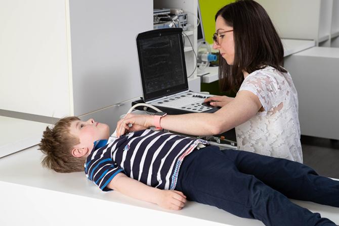 A person uses equipment to take readings of a child lying on a table.