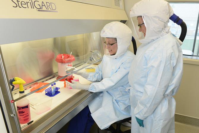 Deux chercheurs portant des combinaisons blanches Bio Safety pendant qu'ils travaillent au laboratoire