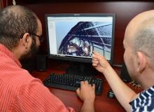 Two people examine an image on a monitor.