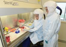 Deux chercheurs portant des combinaisons blanches Bio Safety pendant qu'ils travaillent au laboratoire